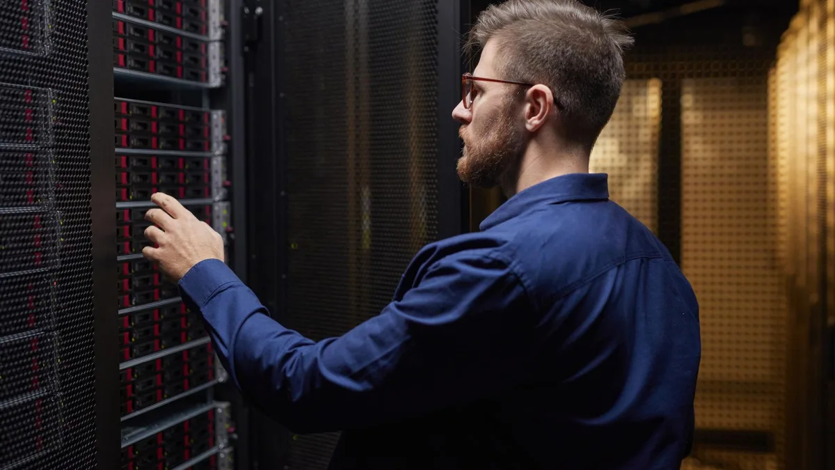Engenheiro de rede analisando infraestrutura de transporte de dados corporativo em rack